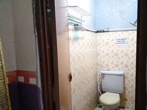 A small bathroom with a toilet, a shower area, and a sign indicating the toilet is for men. - Hotel Alifah 1 Syariah (Tangerang)