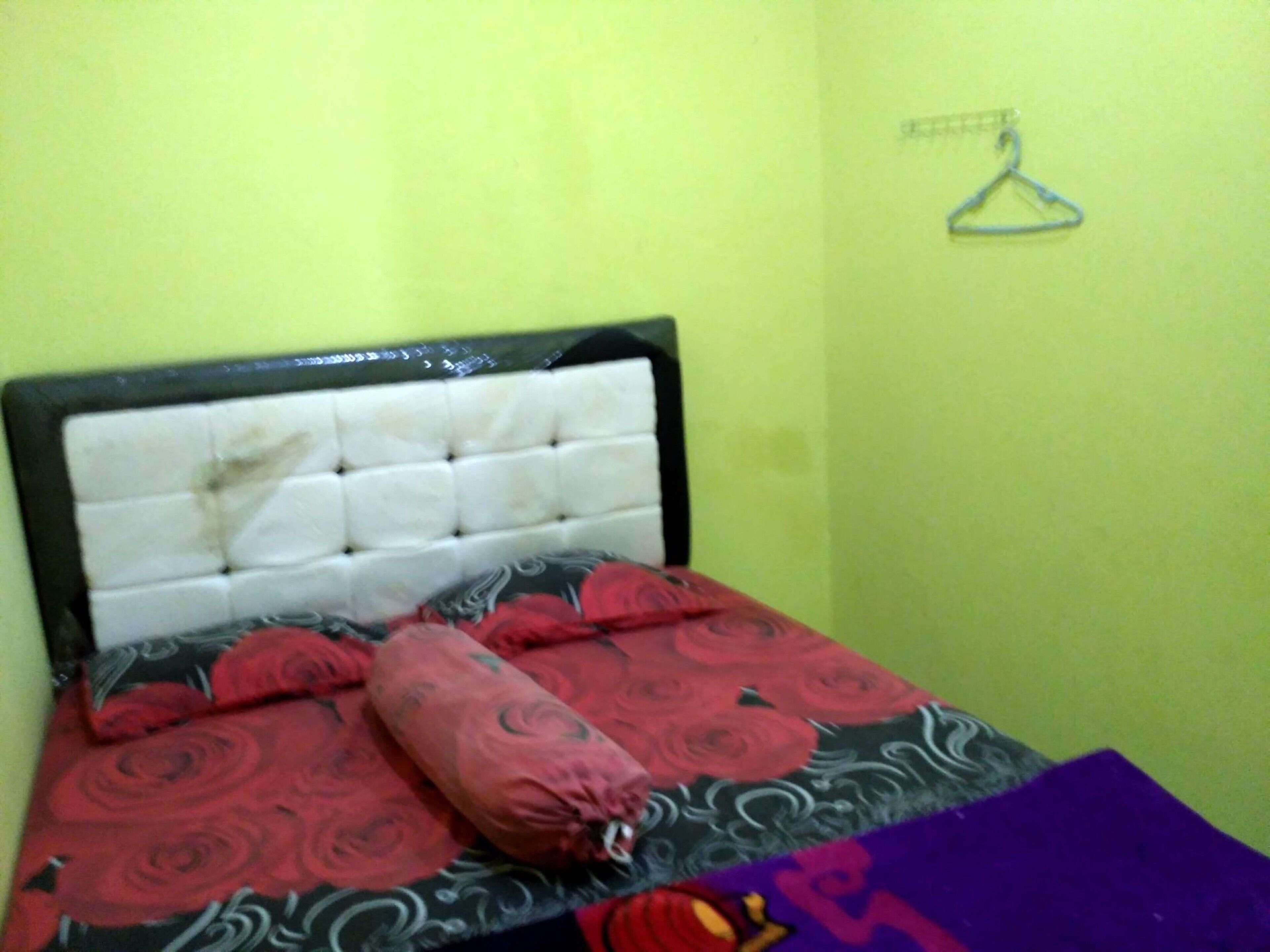 A bed with a tufted headboard, a patterned bedspread, and a purple blanket.