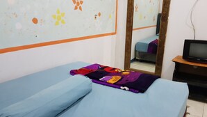 A room with a bed, a television on a wooden stand, and a mirror on the wall. - Hotel Alifah 2 (Tangerang)