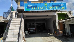The exterior of Alifah 2 Hotel with a signboard, a staircase, and a parked car. - Hotel Alifah 2 (Tangerang)