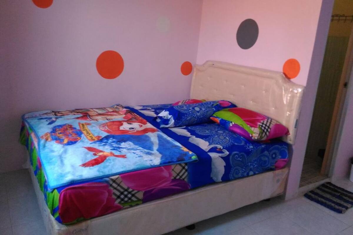 Ein Bett mit farbenfroher Bettwäsche, einem Kopfteil und einer Wand mit Punkten.