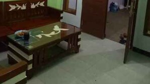 A room with a wooden bench, a small table, and a door leading to another room. - Kampoeng Tourist Homestay (Banyuwangi)