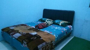 A small, single-bed room with a blue wall and a green carpet. - Kampoeng Tourist Homestay (Banyuwangi)