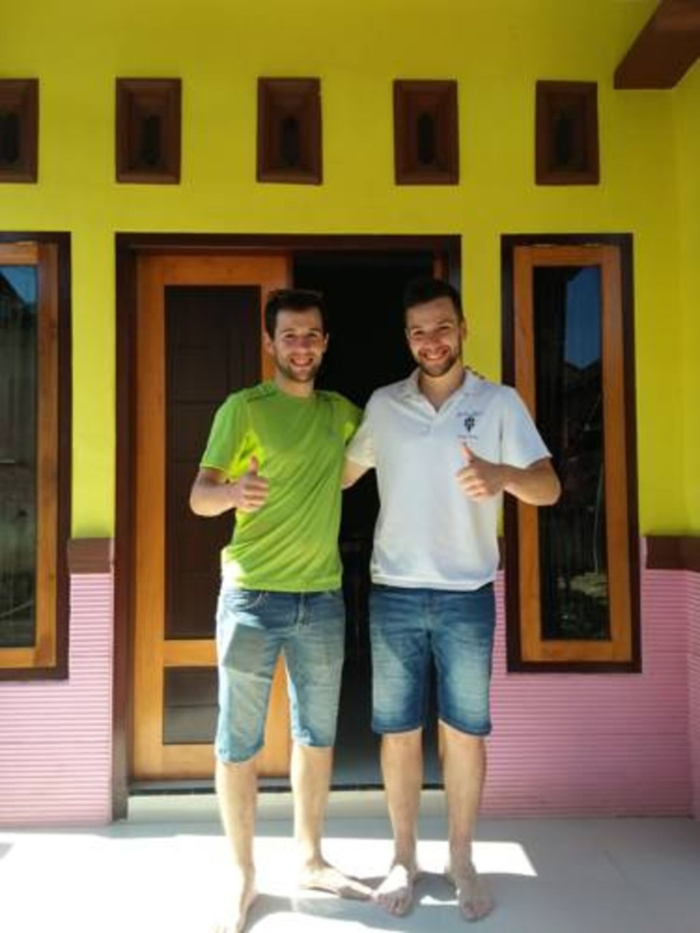 Two people standing in front of a building with a wooden door and windows.