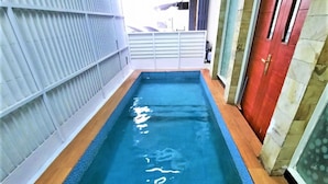 A narrow indoor swimming pool with a tiled floor and a metal railing on one side. - Wisma Acidalia Syariah (Bandung)
