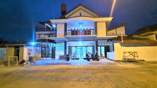 A two-story building with a central entrance and a covered area with motorcycles parked outside. - Wisma Acidalia Syariah (Bandung)