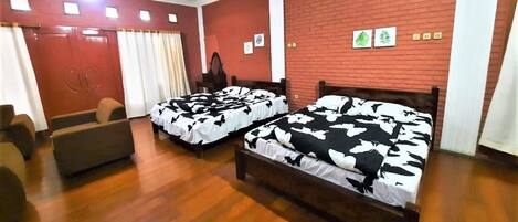 A hotel room with two wooden beds, a sofa, a mirror, and a red brick wall.
