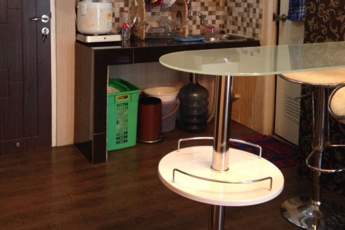 A compact kitchen with a microwave, stove, and a small dining area with a glass table and two chairs.