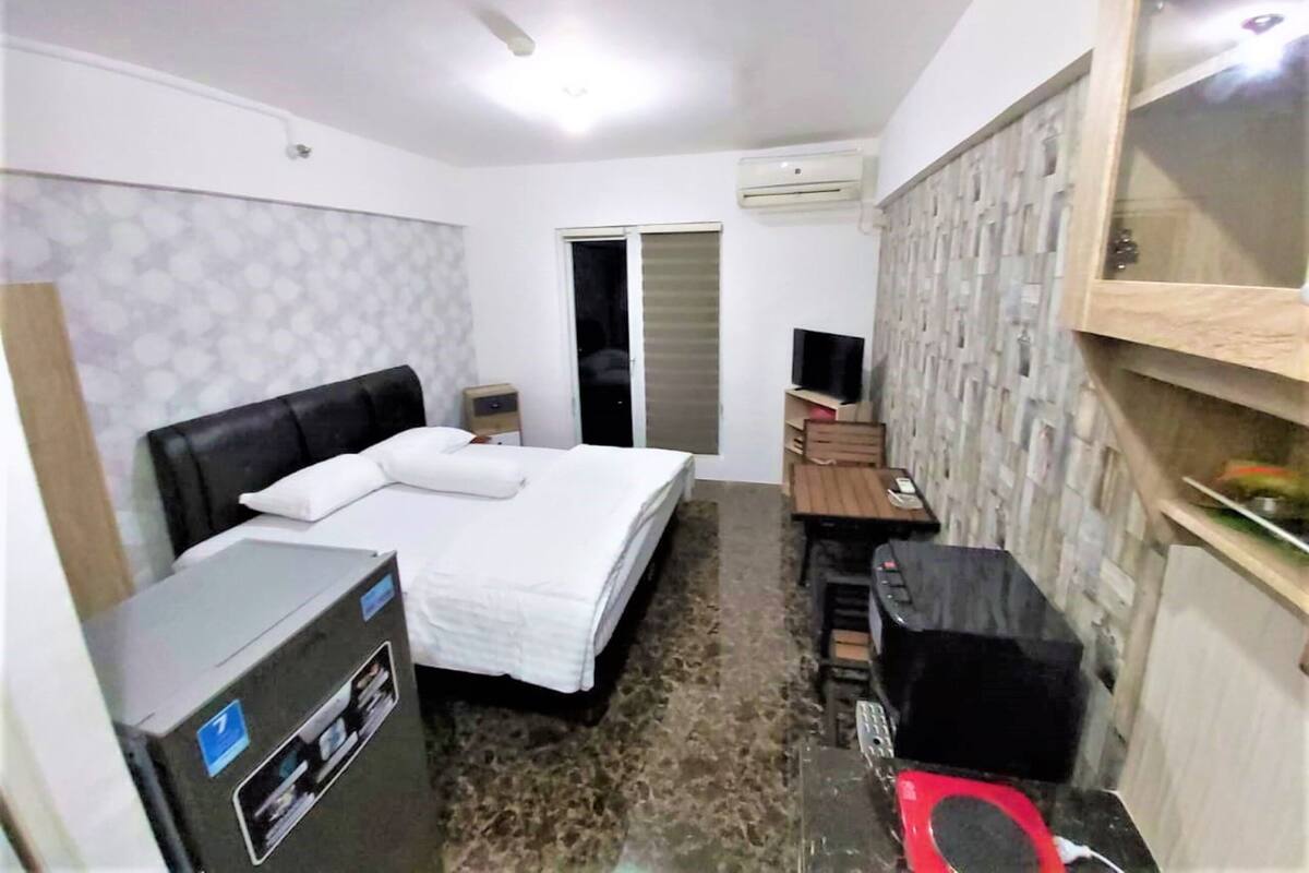 A compact hotel room with a bed, a desk, a television, and a wardrobe.