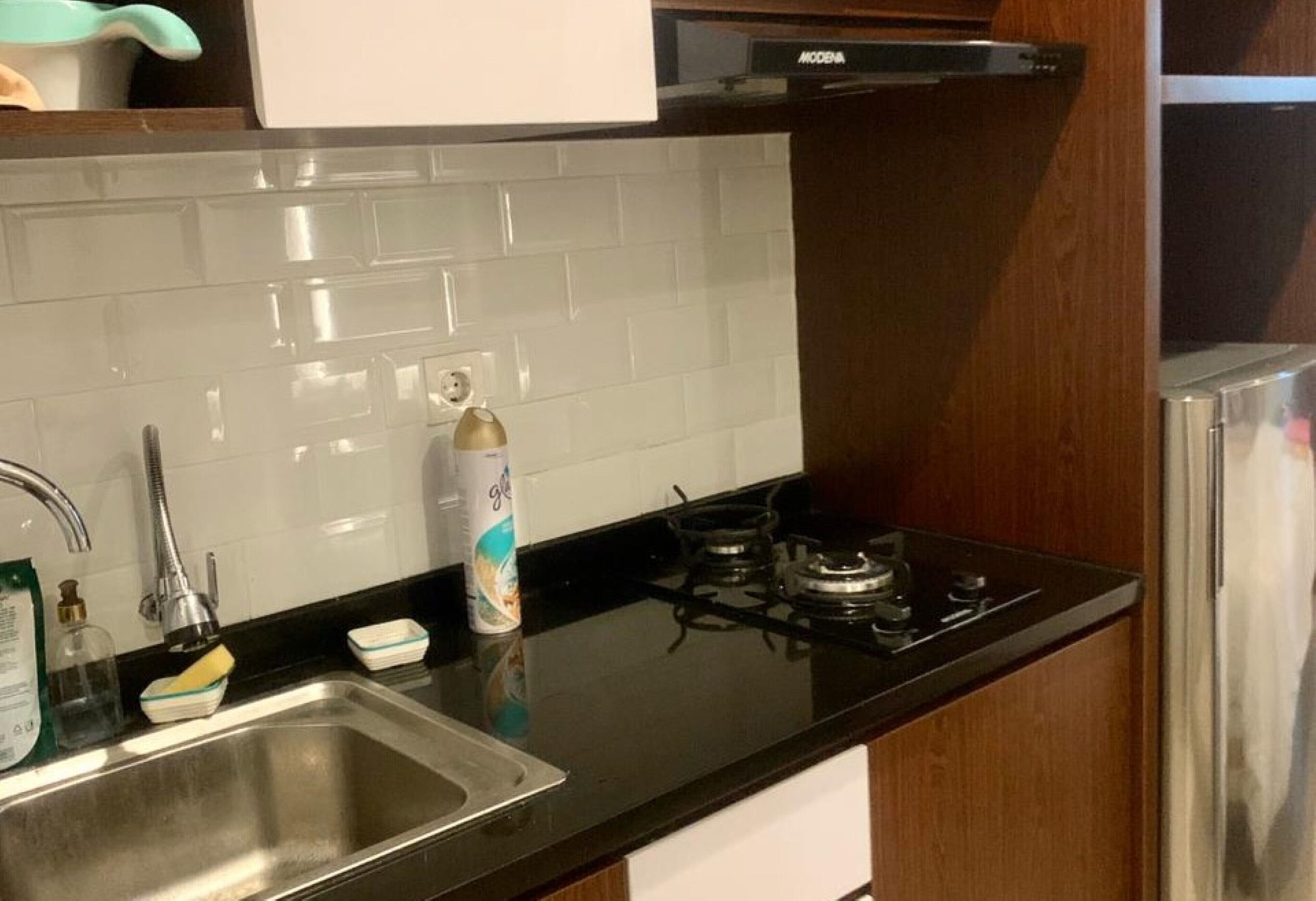 A kitchen with a stainless steel sink, a gas stove, and a white tiled backsplash.