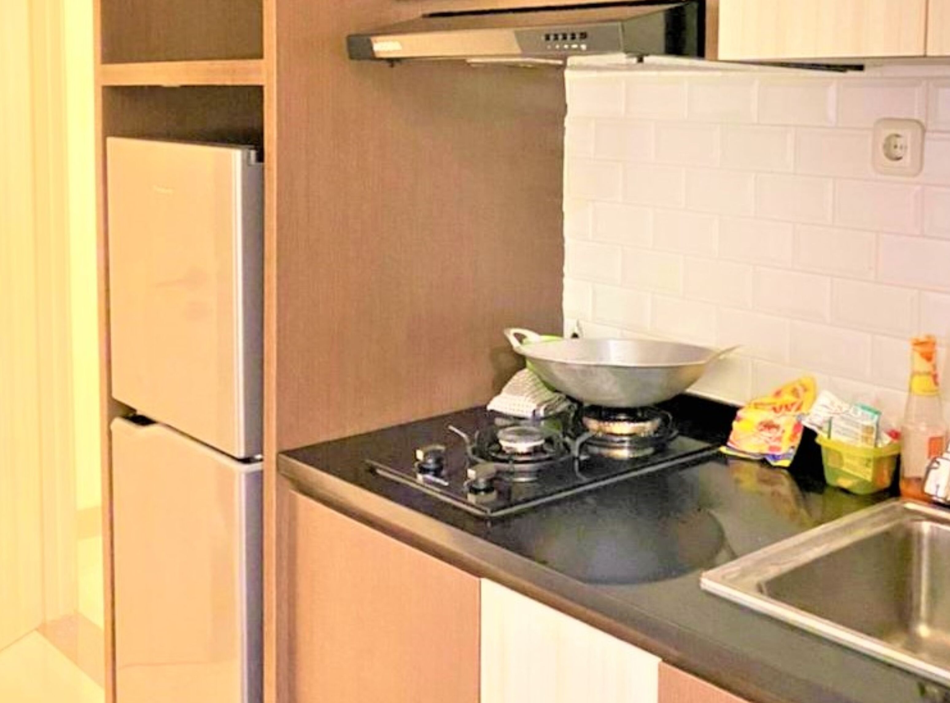A kitchen with a gas stove, a sink, and a refrigerator.