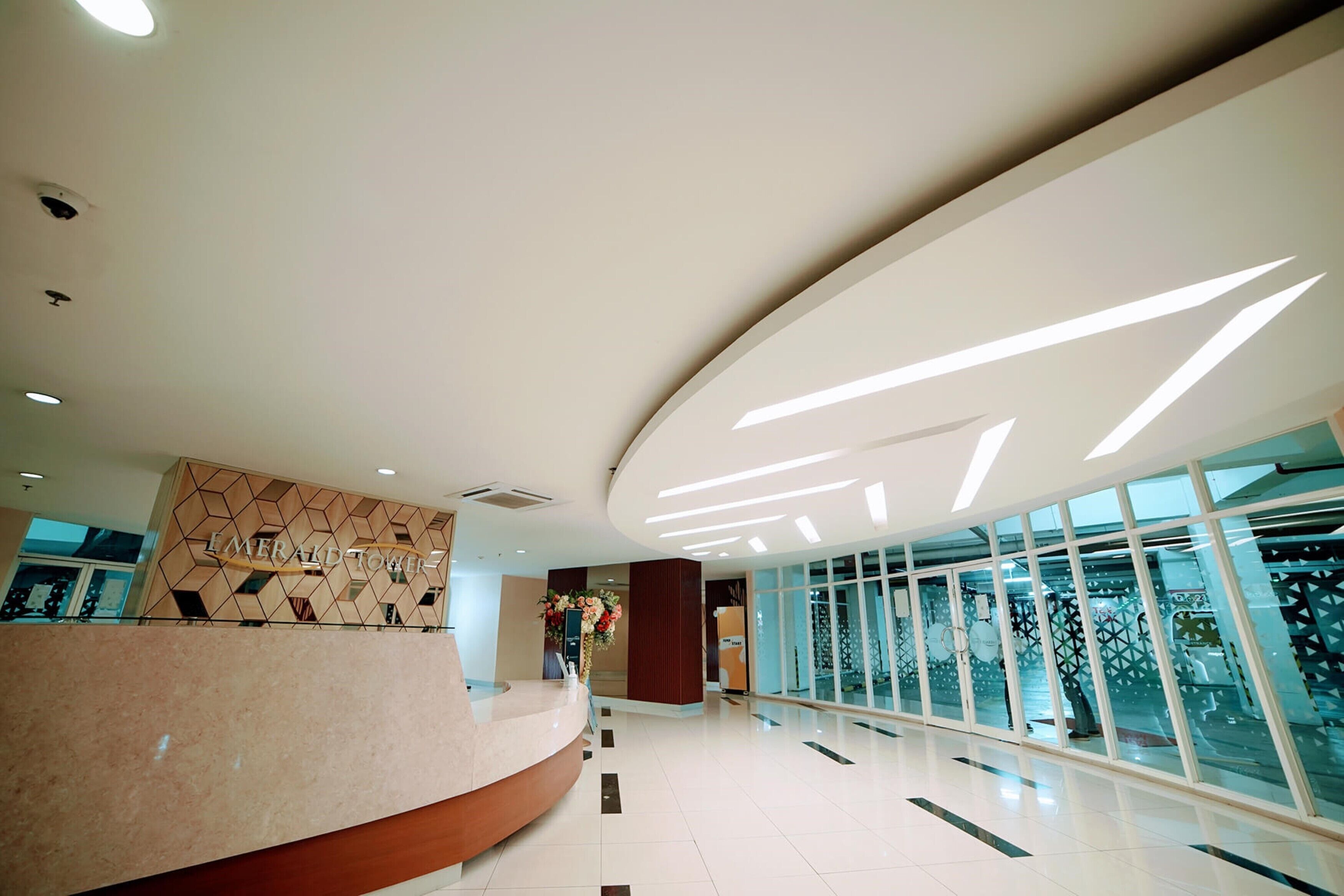 Un hall d’hôtel moderne avec un comptoir d’accueil, un motif géométrique sur le mur et une grande baie vitrée.