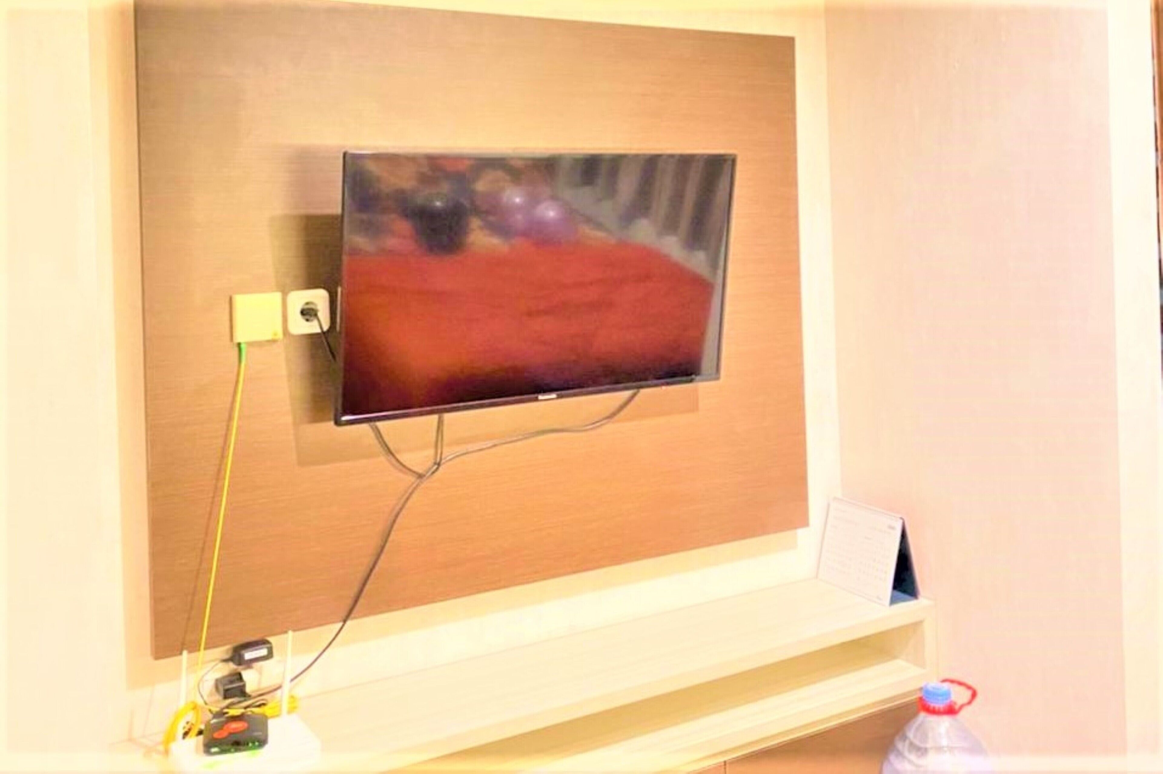 A television mounted on a wooden wall with a cable running to it.