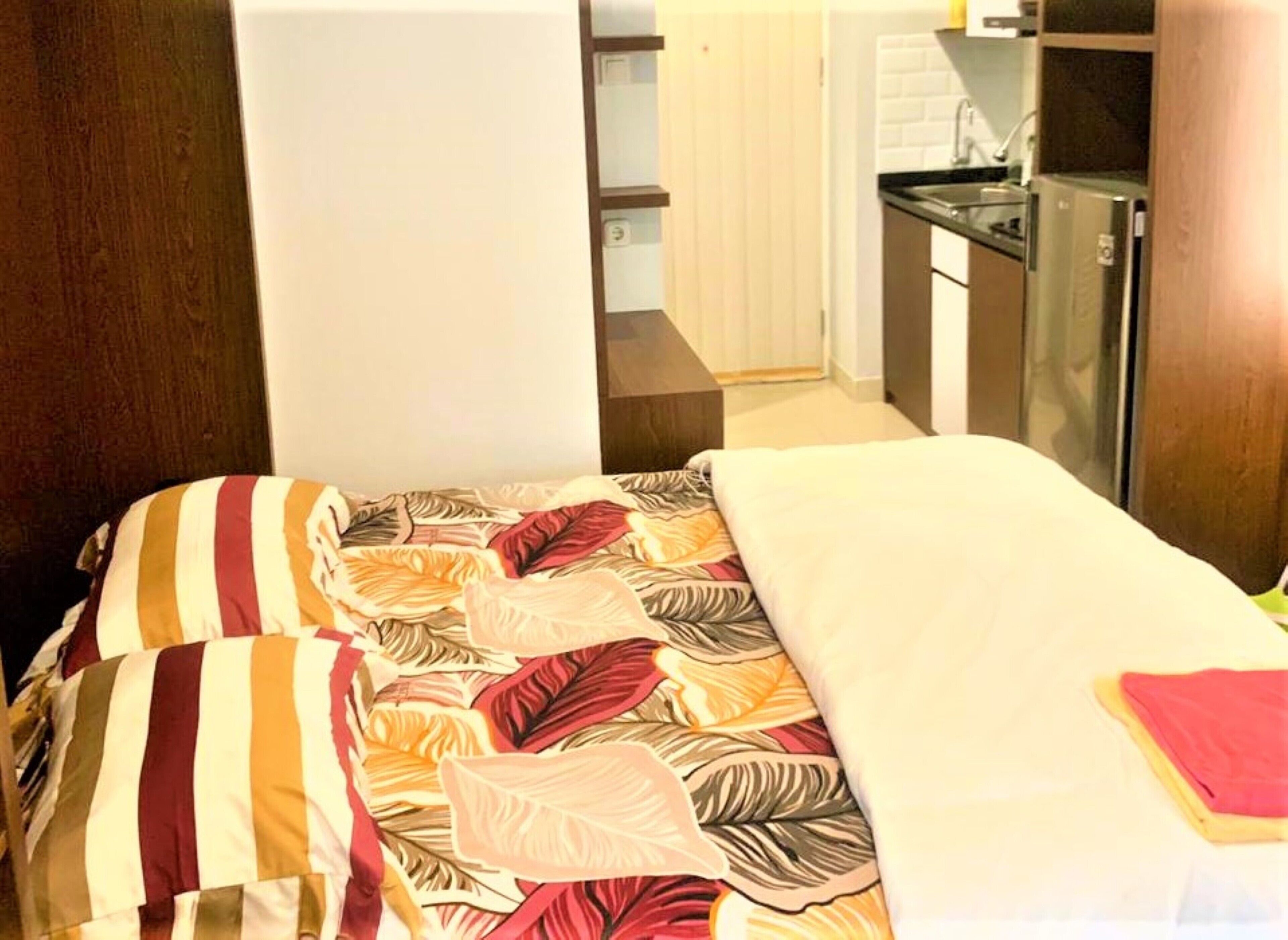 Un dormitorio con cama, mesita de noche y una pequeña zona de kitchenette.