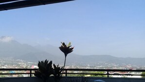 A balcony with a view of a cityscape and mountains in the distance. - Halona Guest House (Batu)