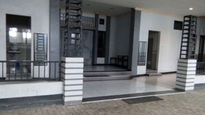 A building with a covered entrance, a staircase, and a tiled floor. - Halona Guest House (Batu)