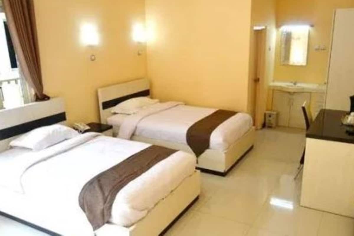 A hotel room with two beds, a desk, and a mirror.