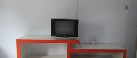 A television on a white and red entertainment unit with a shelf below.