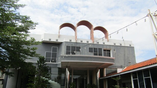 A modern building with a two-story structure, a balcony, and a red-tiled roof.