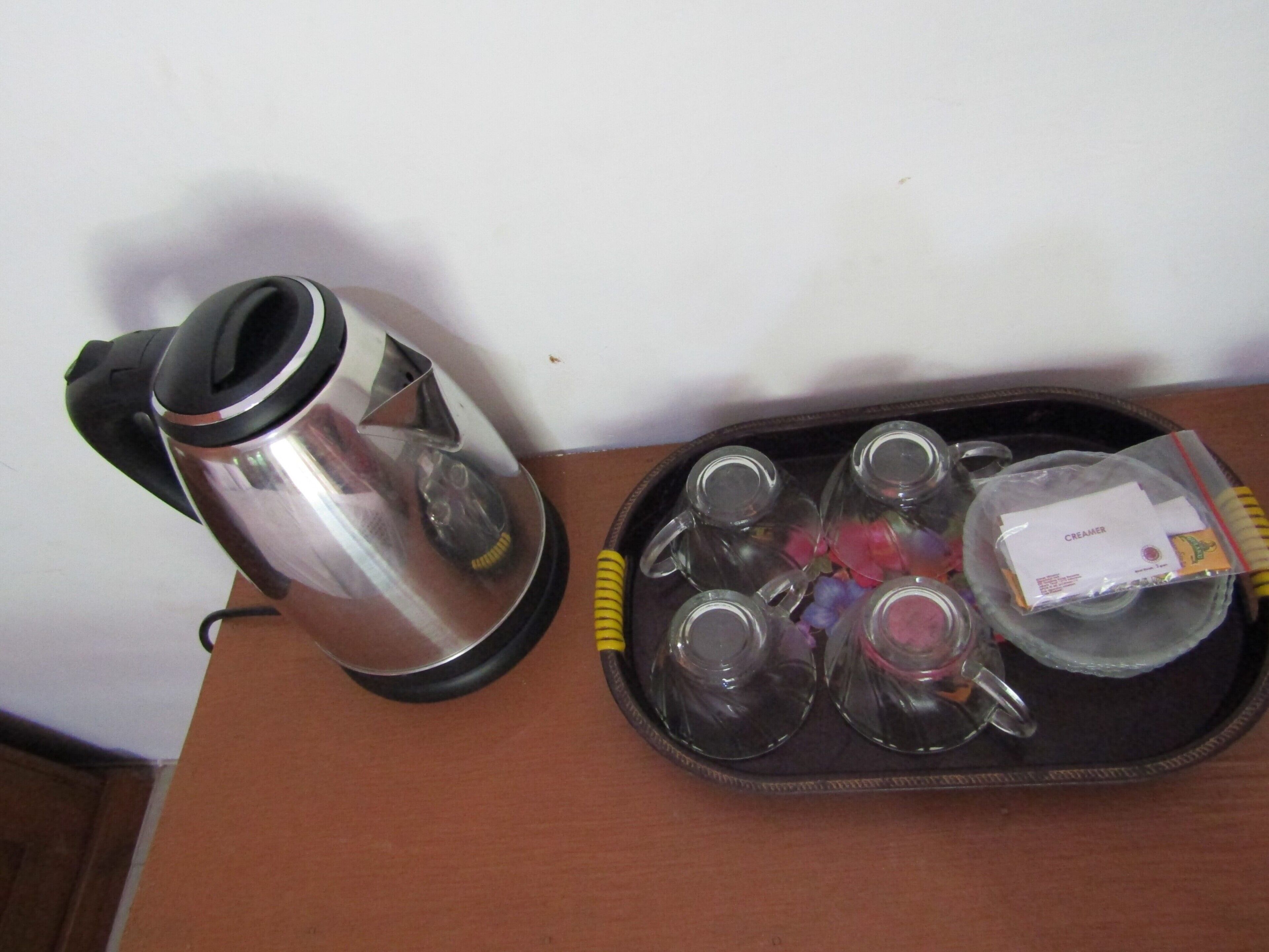 A tray with a coffee maker, several glasses, and a cream container.