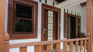 Um edifício com fachada de tijolos, janelas amplas e guarda-corpo de madeira na varanda.