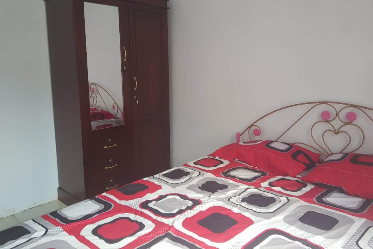Un dormitorio con cama, armario y espejo.
