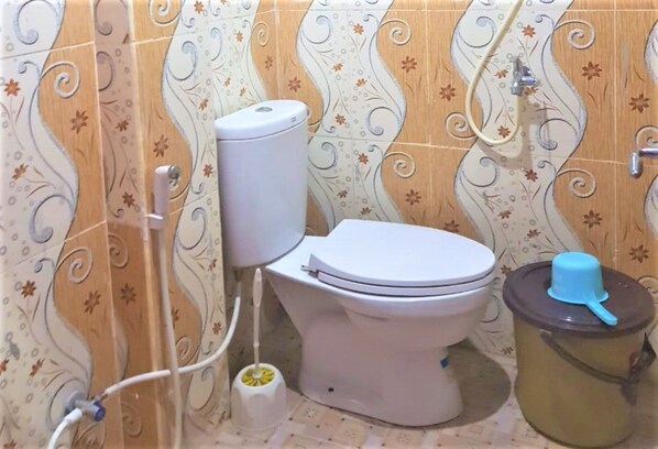 Une salle de bain équipée de toilettes, d’un bidet et d’une poubelle.