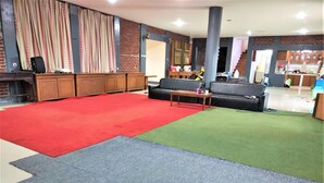 Un vestíbulo amplio con alfombra roja, alfombra verde, un sofá de cuero negro y armarios de madera.