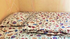 Una cama con una colcha y almohadas estampadas con motivos florales.