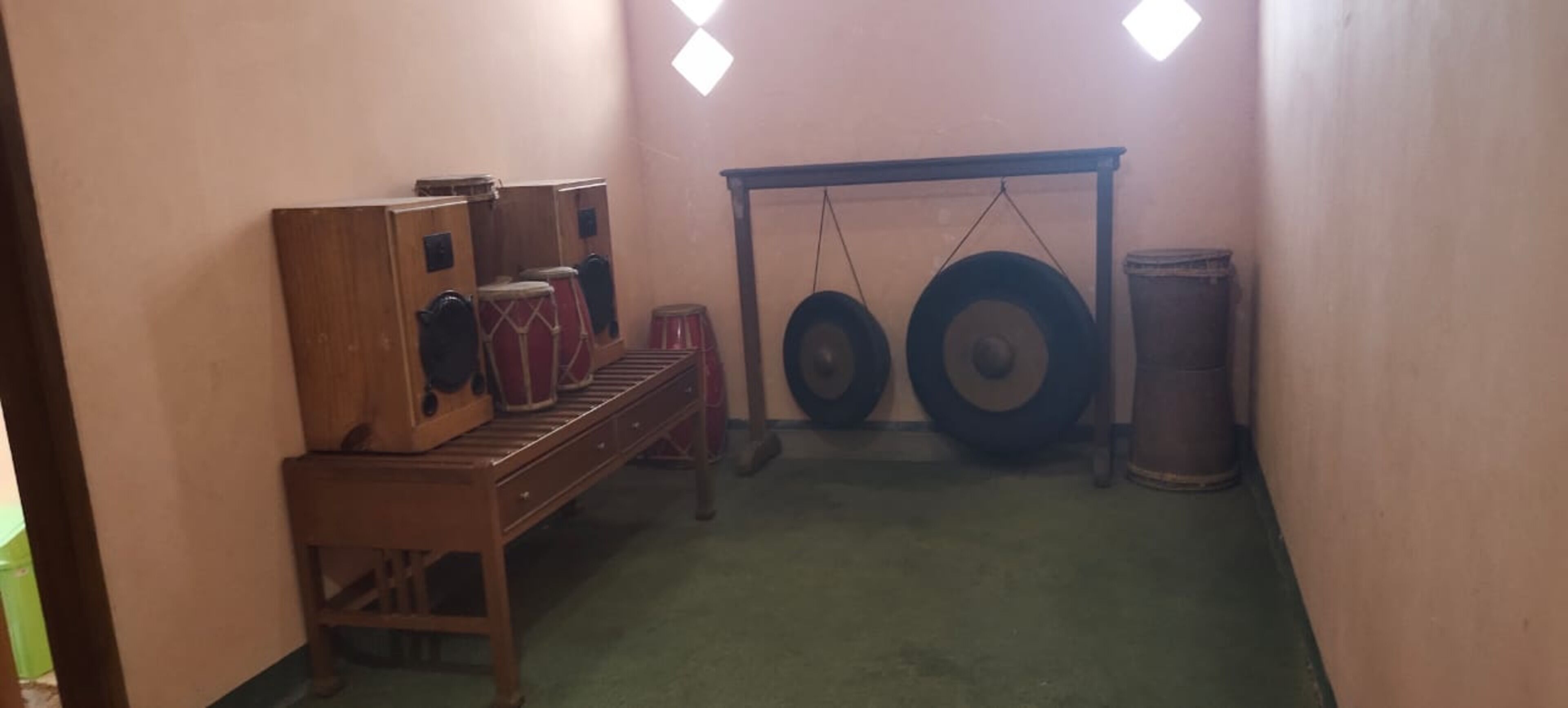 Una habitación con un banco de madera, un set de batería y un estante para guardar tambores.