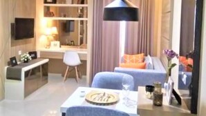 Een moderne hotelkamer met een bureau, stoel, bank en een eettafel met een vaas.