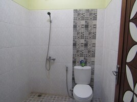 Un baño pequeño con inodoro, ducha y pared con azulejos.