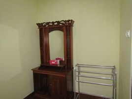 Habitación de esquina con un armario de madera, un espejo y un perchero de metal.