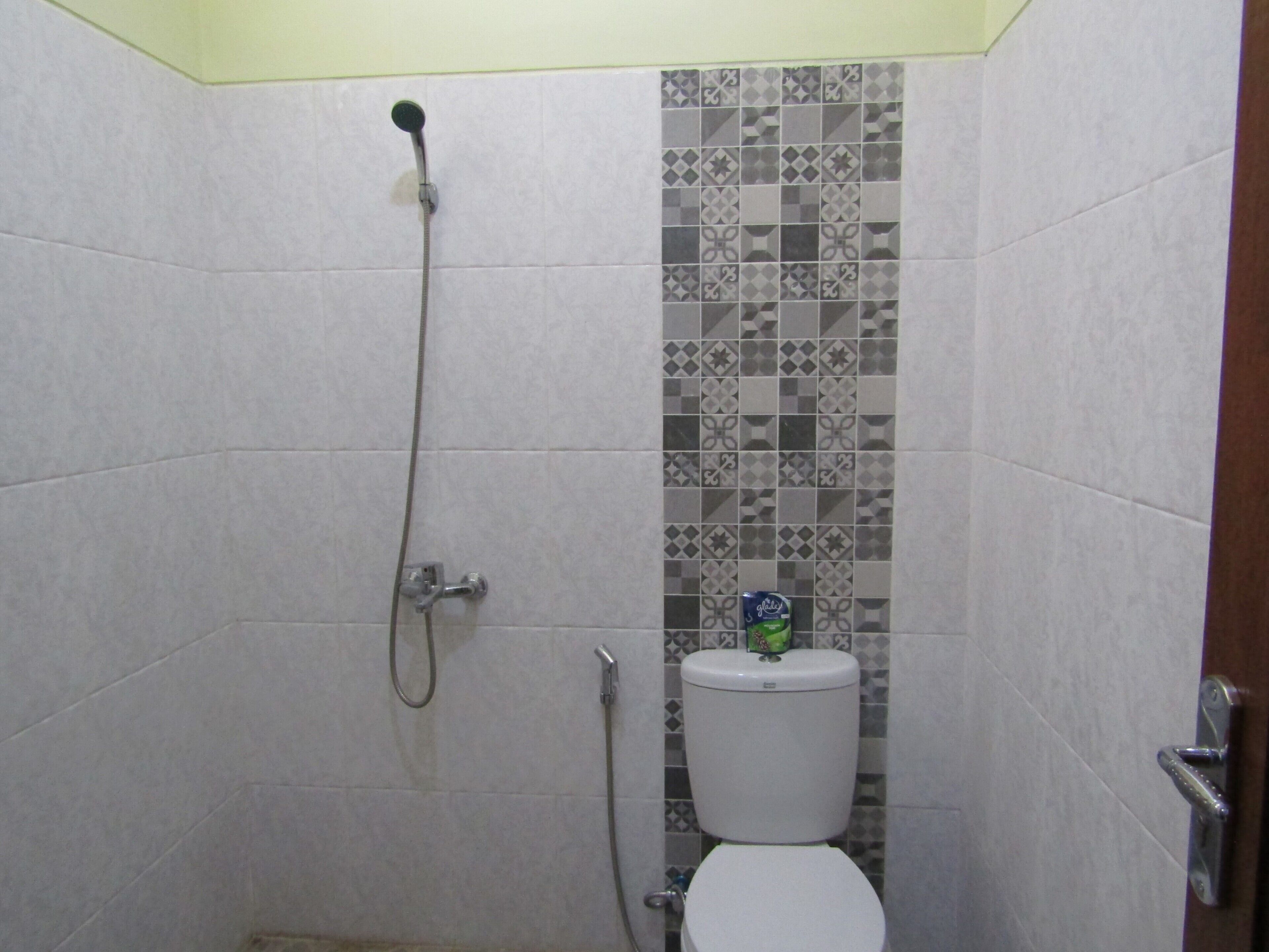 A small bathroom with a shower, toilet, and a tiled wall.