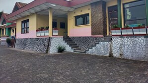 A two-story building with a tiled roof, a covered porch, and a stone-patterned base. - Hotel Wina Wisata (Bandungan)