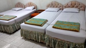 A hotel room with two single beds, each with a white mattress and a green patterned bedspread. The beds have a tufted headboard design. - Hotel Wina Wisata (Bandungan)