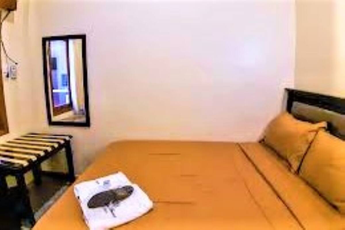 A room with a bed, a small table, and a mirror on the wall.