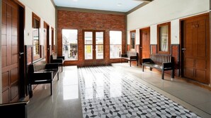A spacious lobby with a patterned floor, wooden benches, and a brick wall. - Rahayu Jawarika Bromo Hotel (Ngadisari)