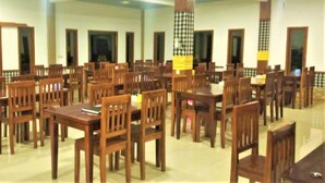 A spacious dining area with multiple wooden tables and chairs, high ceilings, and large windows. - Rahayu Jawarika Bromo Hotel (Ngadisari)