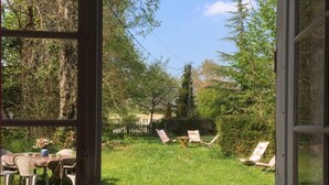 A view from inside a room looking out to a grassy outdoor area with a table and chairs.
