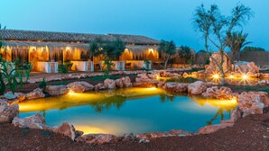 Un hôtel doté d’une piscine, d’un espace extérieur aménagé et d’un bâtiment au toit de chaume.