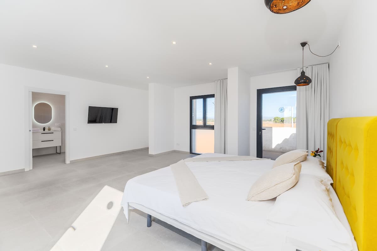 Une chambre moderne avec un grand lit, une télévision et une vue sur l’extérieur.