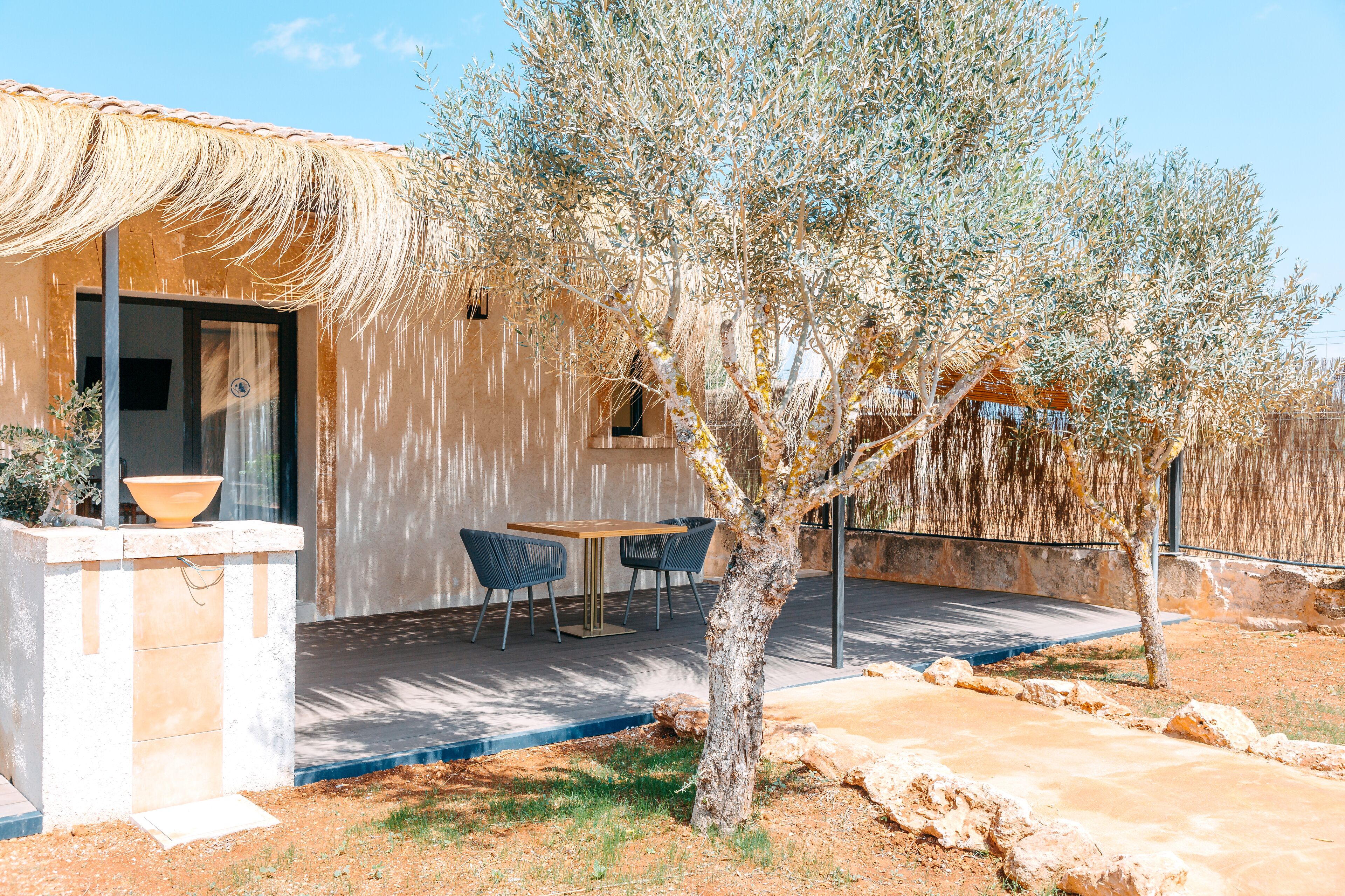 Una casa con patio, mobiliario exterior y un árbol.