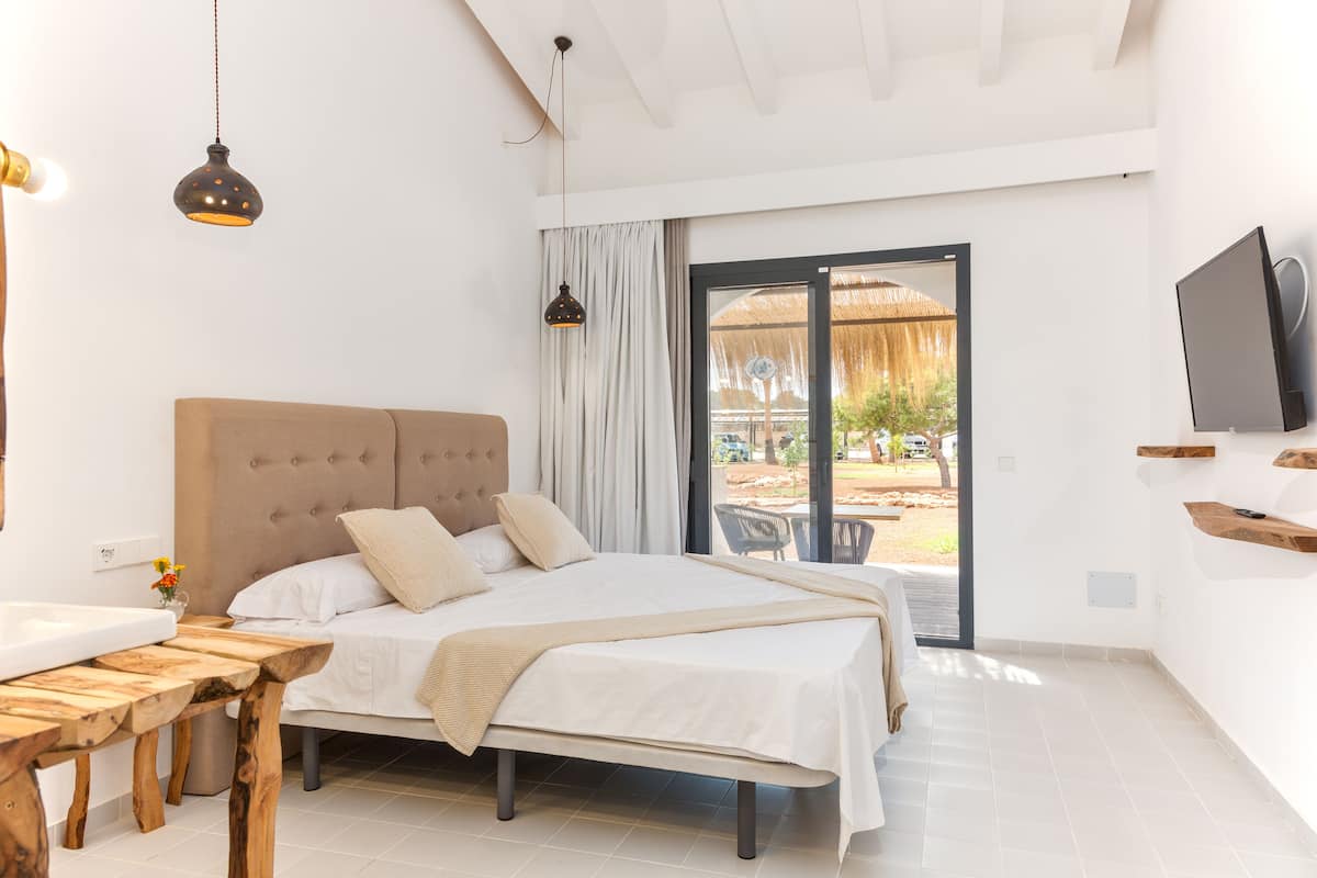 Une chambre à coucher avec un lit, une table de chevet et un téléviseur fixé au mur.
