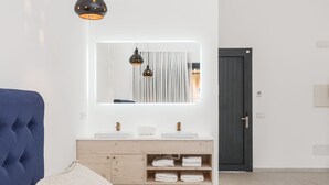 Une salle de bain moderne avec un grand miroir, deux lavabos et une porte sombre.
