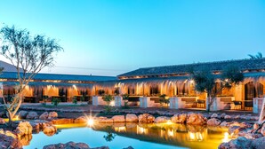 Une cour avec une piscine, des rochers et un bâtiment doté d’un toit en tuiles.