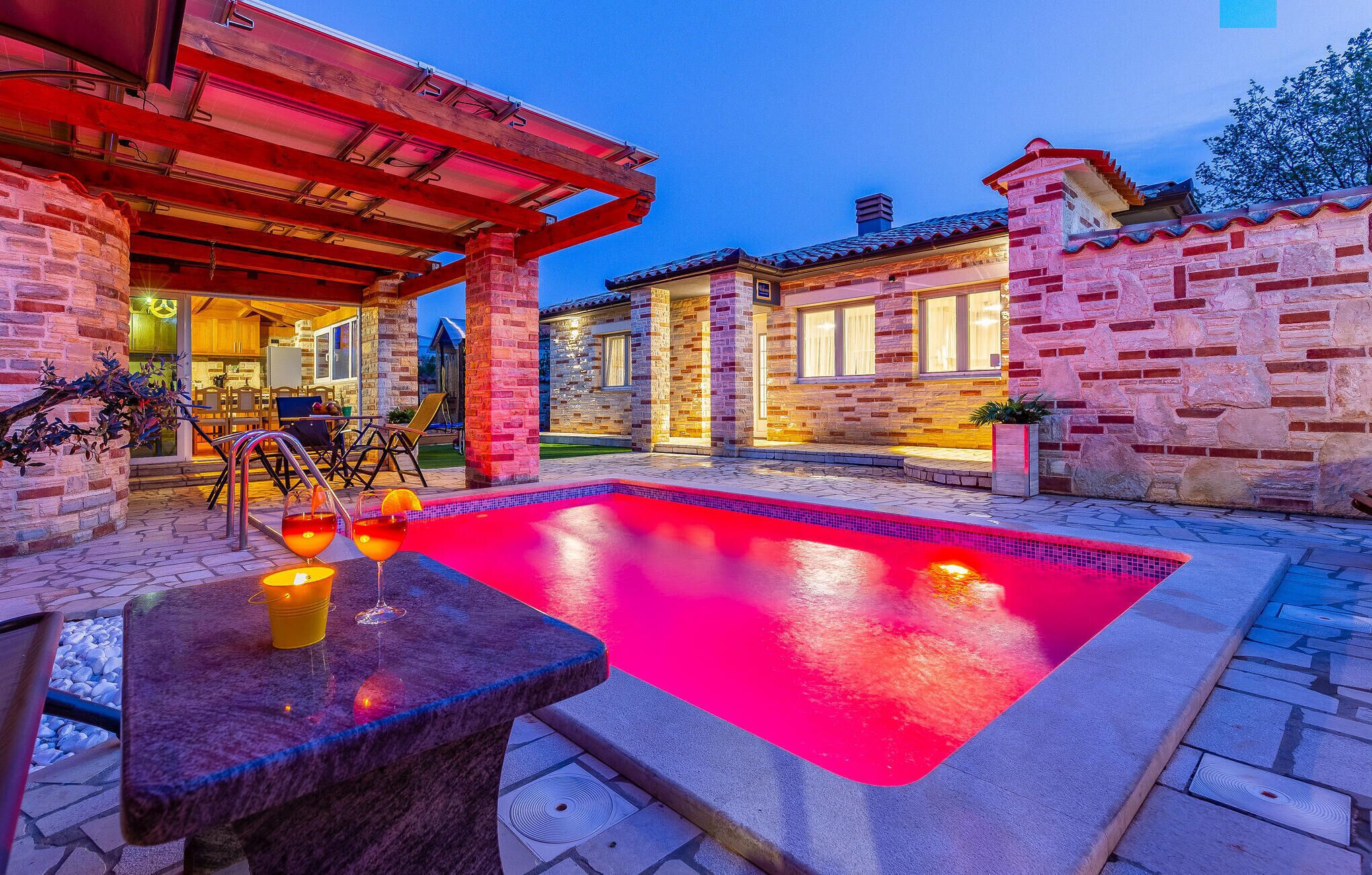 A swimming pool with a red tint, surrounded by a patio area with outdoor furniture.
