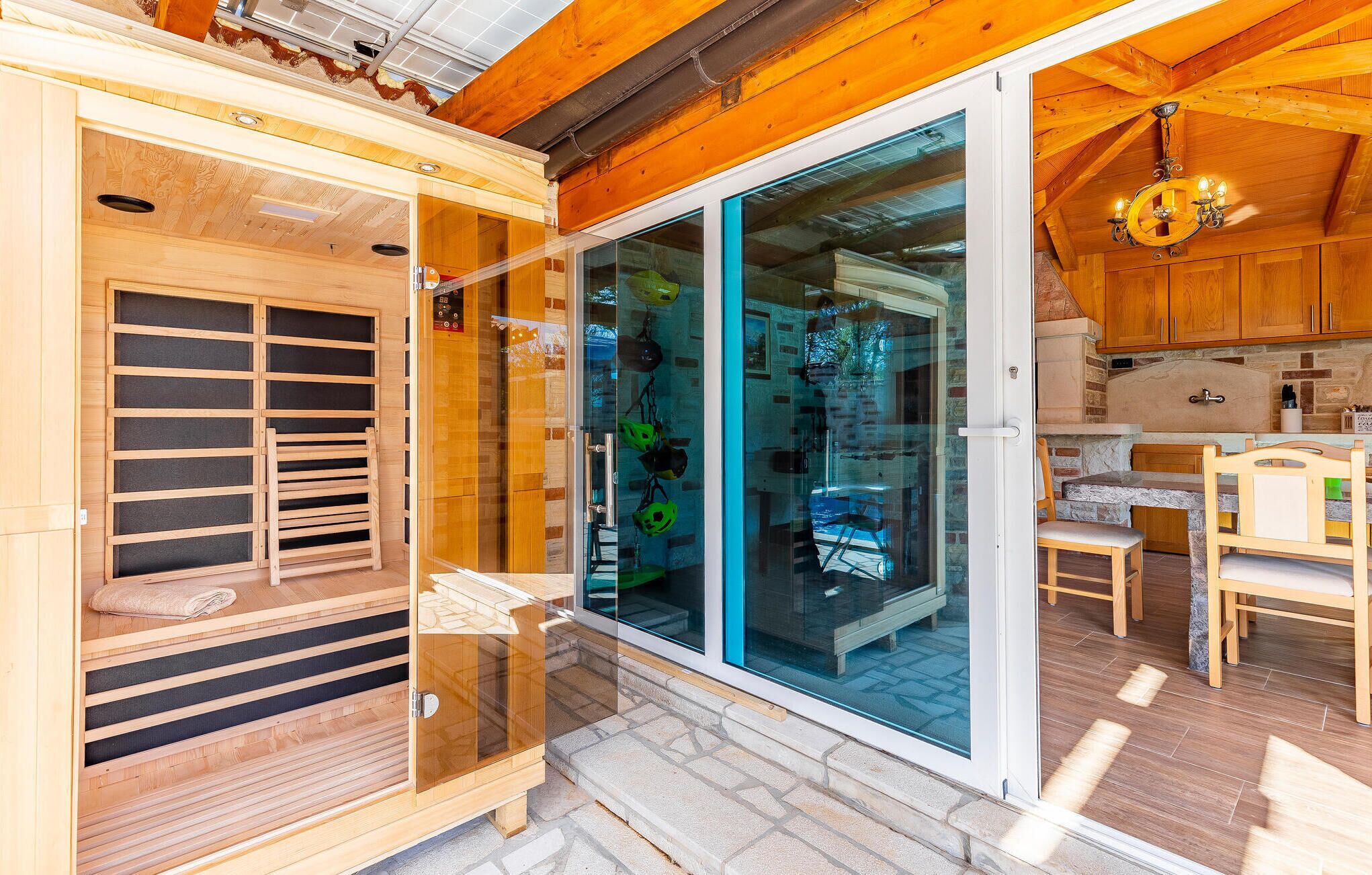 Eine Holzhütte mit Sauna, einer Glastür, die auf eine Terrasse führt, und einer Küchenzeile.