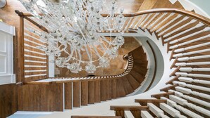 Una escalera de caracol con escalones de madera y barandillas blancas, que conduce a un candelabro.