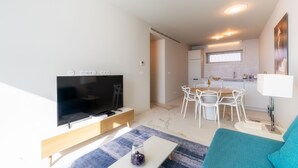 Un salon moderne avec un téléviseur à écran plat, une table basse et un canapé de couleur turquoise.